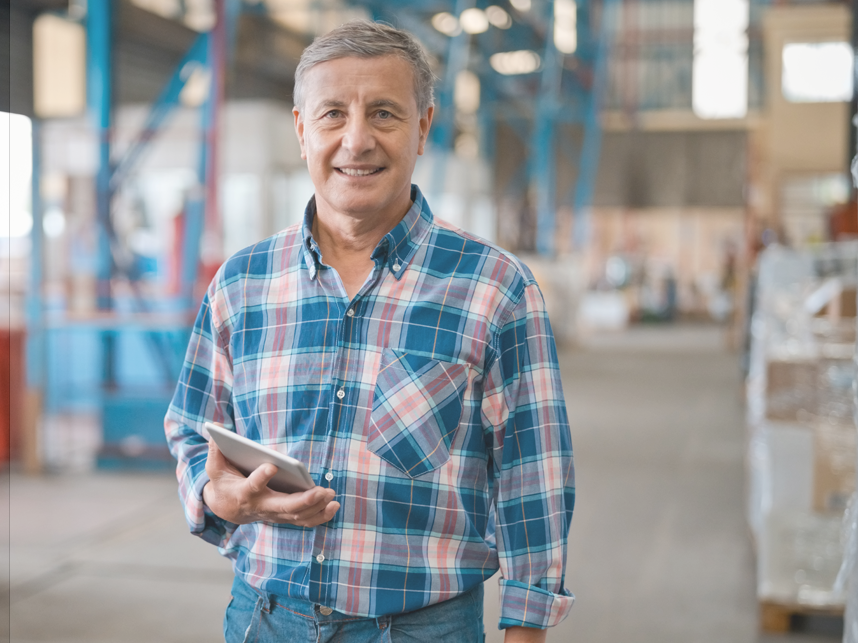 CTA -BodyImageFullBleed-istock1364215824-858x643px Mature male manager in warehouse smiling at camera wearing a flannelette shirt