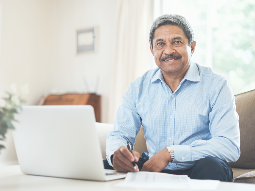 EST -FullBleedModule-iStock-90286366285-8x643px A senior man using a laptop at home while smiling to camera.