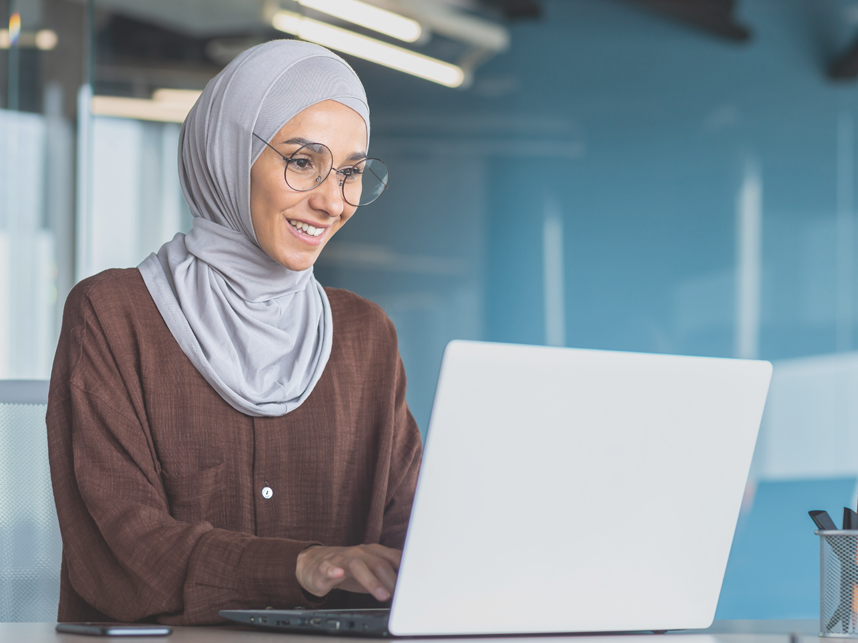 Employers-FullImage-858x643-iStock-1465624021 Woman wearing a hijab working on finance documents on her laptop.