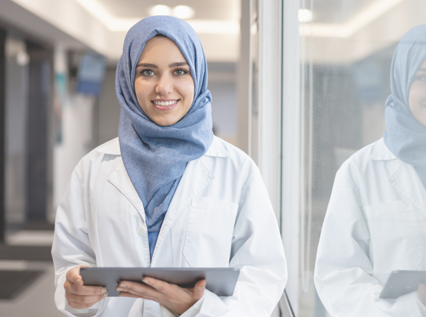 FinancialSupport-MediaTextSplitModule-618x460px-iStock-1404962399 Lady at work holding a tablet and smiling at the camera.<br />