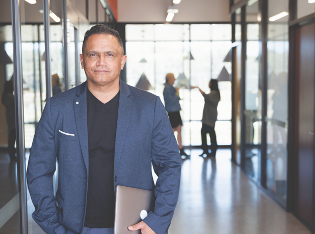 FinancialSupport-MediaTextSplitModule-618x460px-iStock-1417514842 Man in a navy blazer holding laptop and looking at the camera.