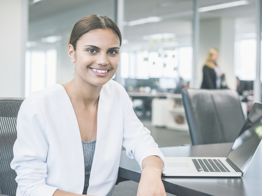 WFA-Employees-Full-Image-858x643-iStock-504334780v2 Business woman at desk looking at the camera and smiling.