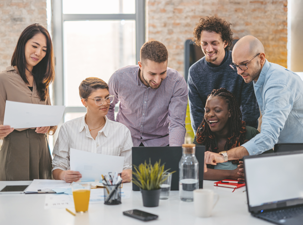 Generic -BodyImage-iStock1465568487-618x460 A diverse business team crowd around a laptop cheerfully working together on a project