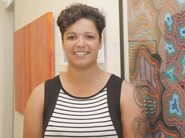 RAP-JasminSarin-Module618x460px-June24 Artist Jasmine Sarin facing forward smiling in front of an Aboriginal Artwork