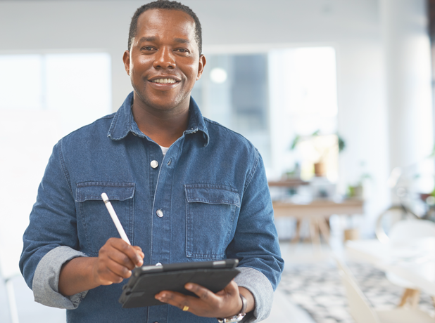 SEA-FullBodyImage-iStock-1473510724-618x460px Happy middle-aged African American man writing on touchscreen tablet in office environment.