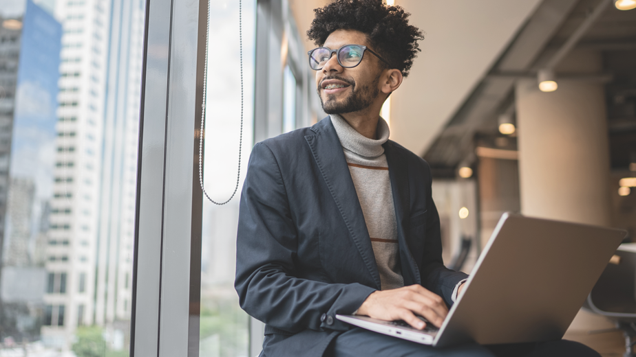 SEA BodyImage-iStock1424988699-924x520px Young hispanic businessman with curly hair contemplating in the office looking through the window
