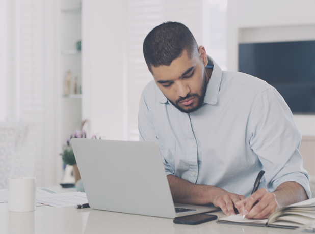 The MTC Difference-MediaTextSplitModule-618x460px-iStock-1589358749 Middle Eastern man working on financial documents at his desk.