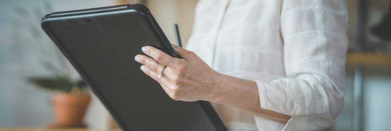 Reports - CampaignLandingPageBanner-1248x420px - June24 Mid-torso shot of woman in white shirt holds a report document