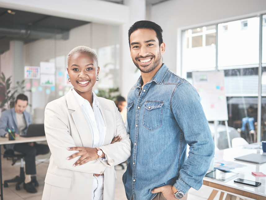DES-Full Image-Media and Text Split Full bleed-iStock-1553115779-858x643 Portrait of two employees in a casual office setting looking at the camera and smiling.