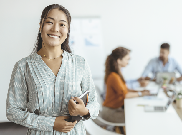 Employers-CampaignTitleCards-iStock-1330547068-518x440px A woman smiling at the camera in an office.