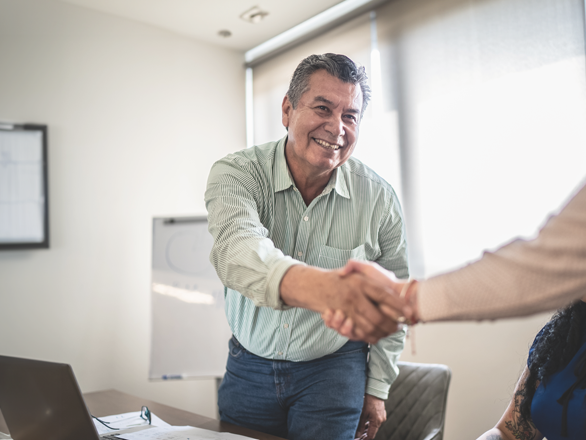 Employers-CampaignTitleCards-iStock-1407182787-518x440px an older man standing up from his desk shaking someones hand.