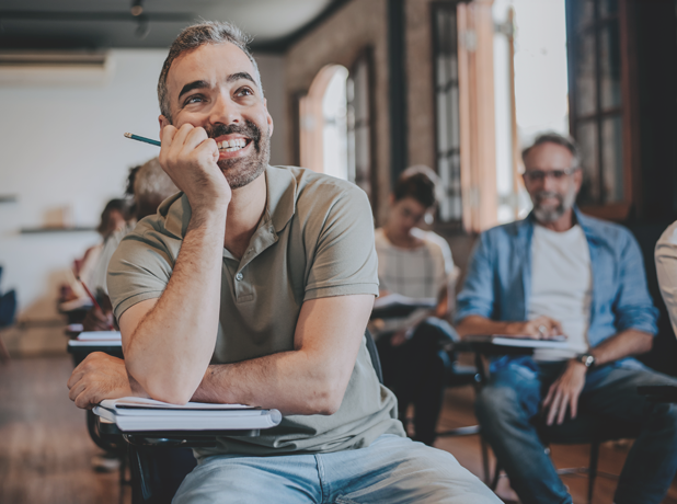 Generic -BodyImage-iStock-1465886929-618x460 Portrait of a middle-aged man in an adult classroom setting, smiling and looking looking towards the teacher.
