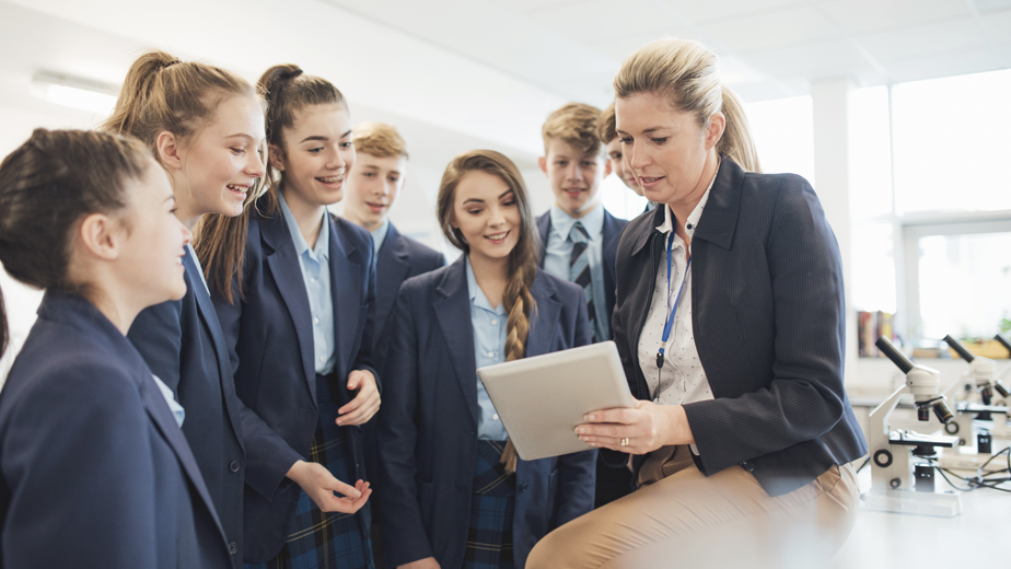 NSWP-ProgramPageHeaderBanner-924x520px-iStock-901967544 A female teacher talking to a group of students in a science room.