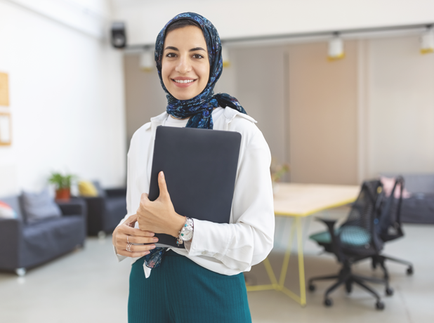 PBAS-BodyImageModule-iStock1358221418-618x460px Portrait of a middle eastern businesswoman at office. Woman executive wearing headscarf smiling at camera holding a file.