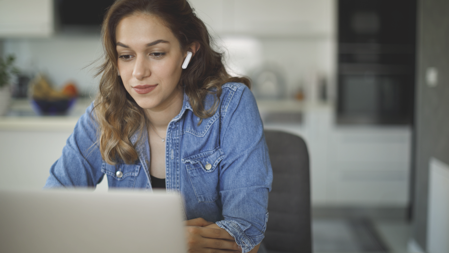 SEA-ProgramHeadeBanner-iStock-1441924722 -924x520px Smiling young woman with bluetooth headphones attends an online course at home