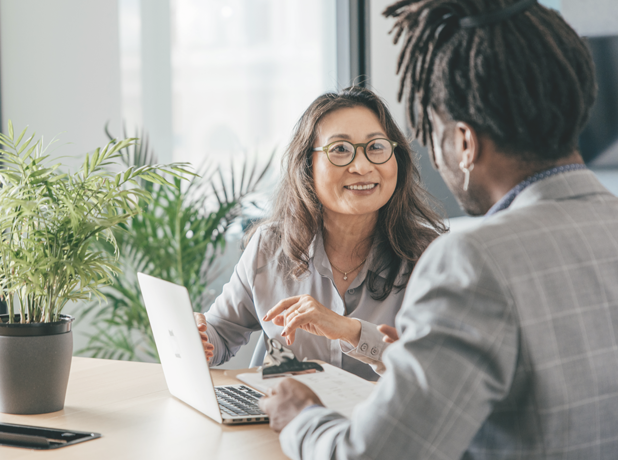 SEA -BodyImage-iStock-1412758551-618x460px Two multicultural people sitting at desk having a one on one conversation about business.