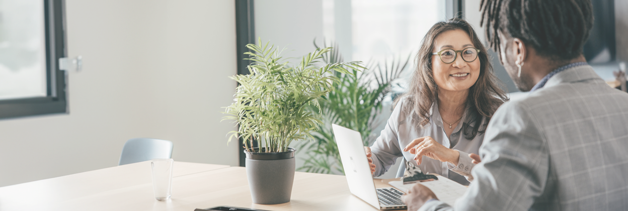 SEA-CampaignHeaderBanner-iStock-1412758551-1248x420px Two mixed-race executives at work in the office discussing some paperwork.