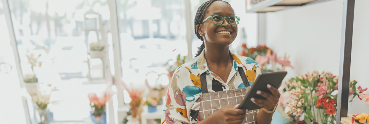SEA-CampaignHeaderBanner-iStock-1569566040-1248x420px A 27-year-old African-American female entrepreneur owns a fresh flower shop, using a digital tablet. Stock
