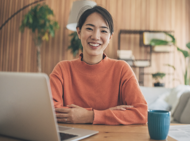 SEE-BodyImageModule-iStock-1560524073-618x460px Young asian woman sitting in front of laptop smiling at camera