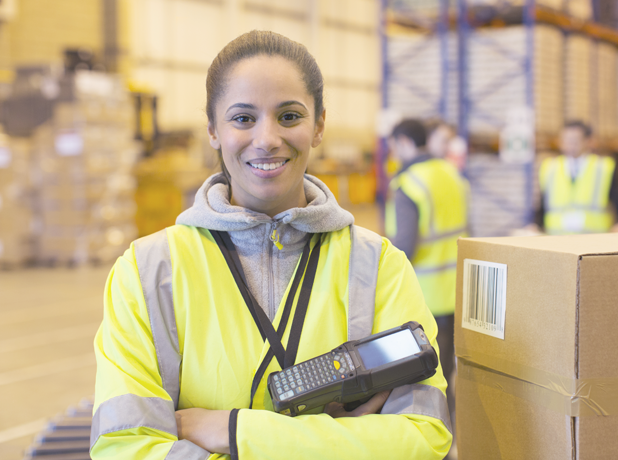 SEE - Full Image - Media and Text Split 618x460px_7c young woman in high vis smiling at camera standing in warehouse