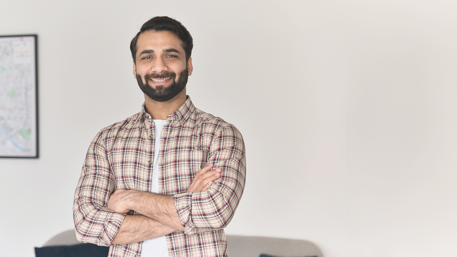 SEE- ProgramHeaderBanner-istock1310078148- 924x520px Portrait of young happy indian business man looking at camera standing with arms crossed at home office.