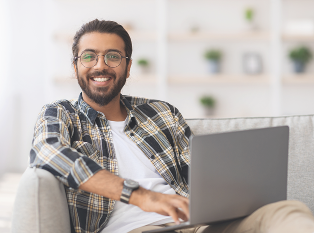VET-BodyImageModule-Istock1351342354-618x460px Positive Indian male reclining on couch with laptop whilst completing online study.