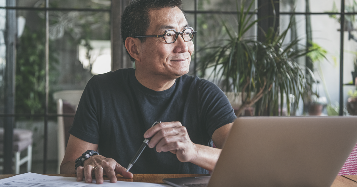 Employment-Featured Image Size -1200x628px A person working on a desk and looking outside a window.