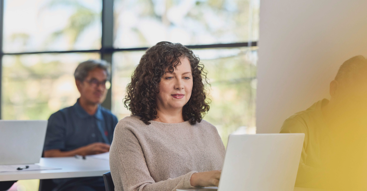 Woman sitting in a class and looking at her laptop
