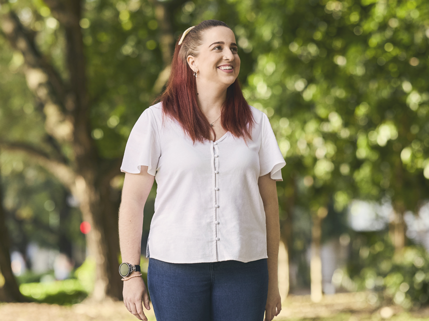 Lady in park looking into the distance and smiling. 