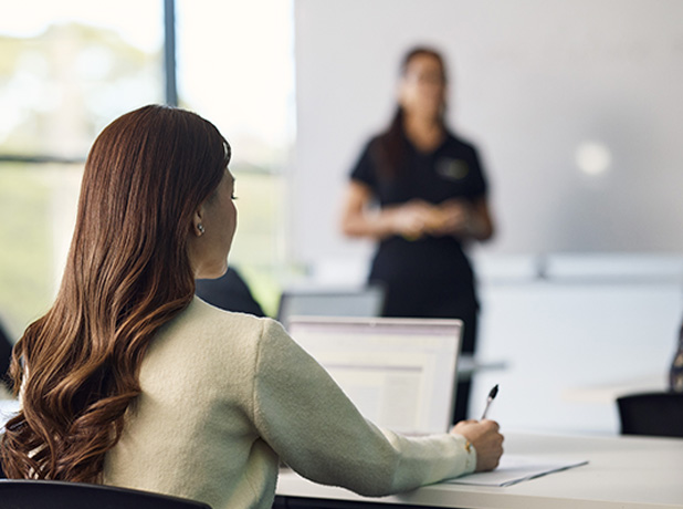 Smiling woman in headscarf and glasses sitting at desk on laptop