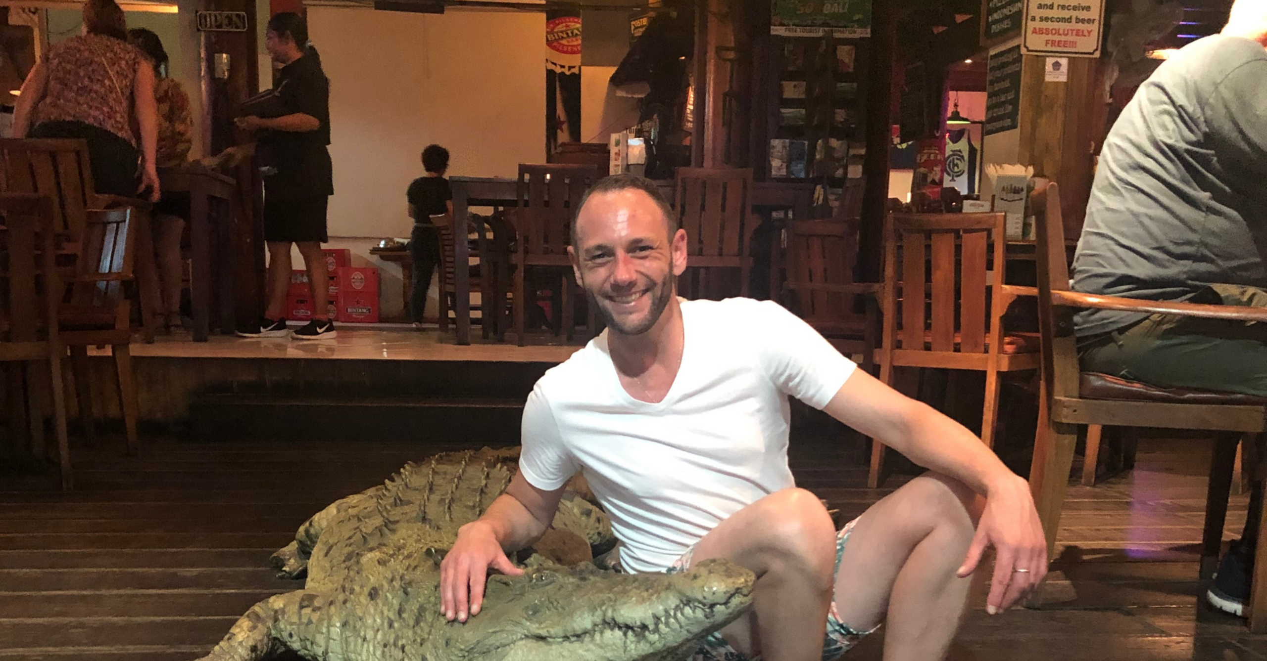 Tristan sitting on stairs with a fake crocodile, while on vacation.
