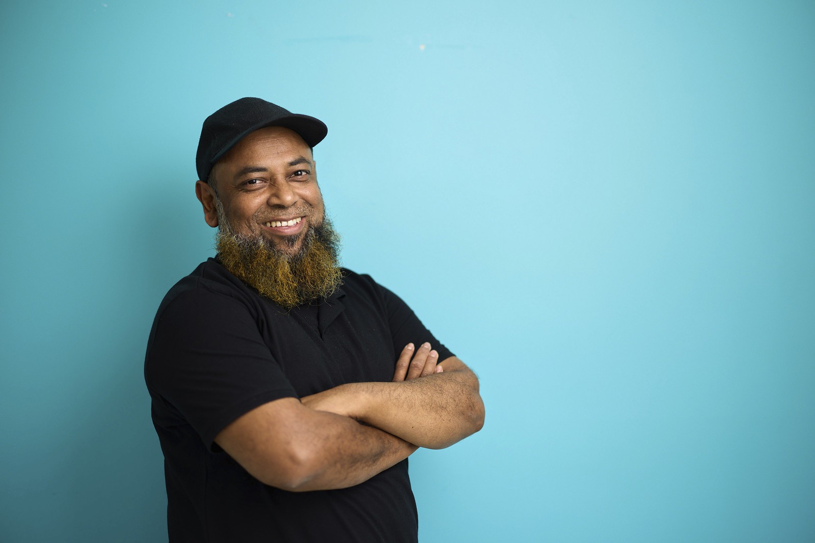 Omar smiling with arms folded in front of a blue background